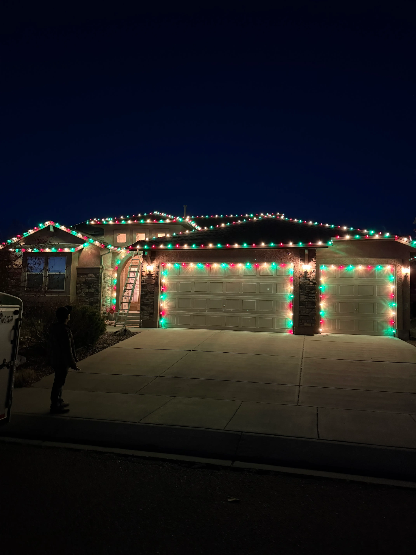 Christmas lights installation Colorado Springs - professional holiday lighting on residential home with red and green LED roofline lights, garage door lighting, and complete outdoor display