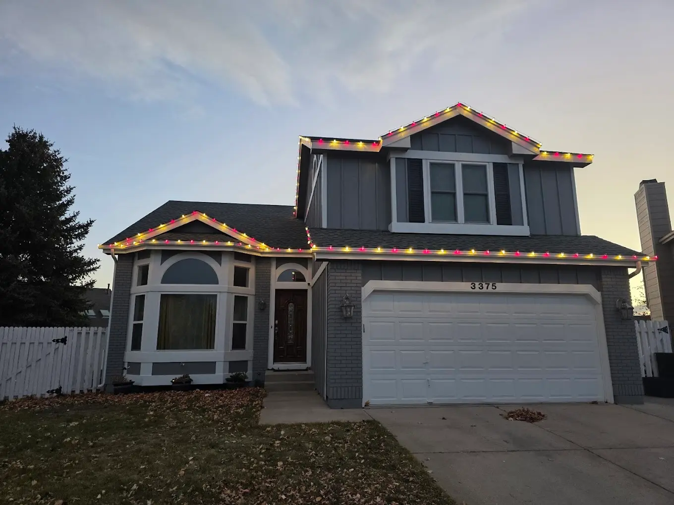 Christmas light installation Colorado Springs two-story home - professional multicolor LED lights featuring red yellow green bulbs on roofline, residential holiday lighting services